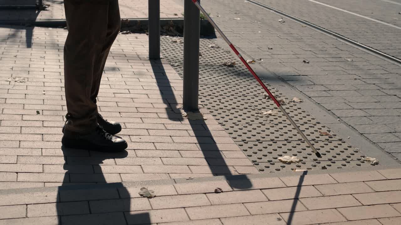 Lone blind man detecting tactile tiles, walking to pedestrian crossing safe road