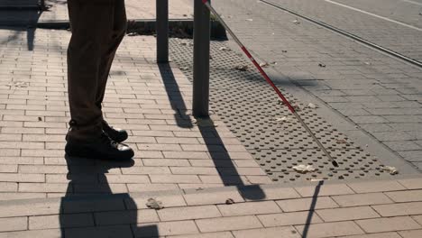 lone blind man detecting tactile tiles, walking to pedestrian crossing safe road