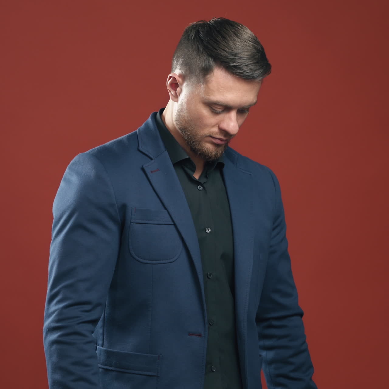 Businessman on red studio background. Portrait of a handsome man in dark suit. Successful man holding a folder and writes on it indoors.