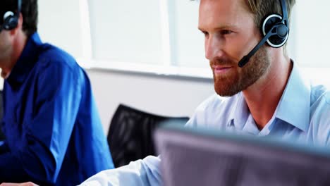 Male-executive-with-headset-working-on-computer