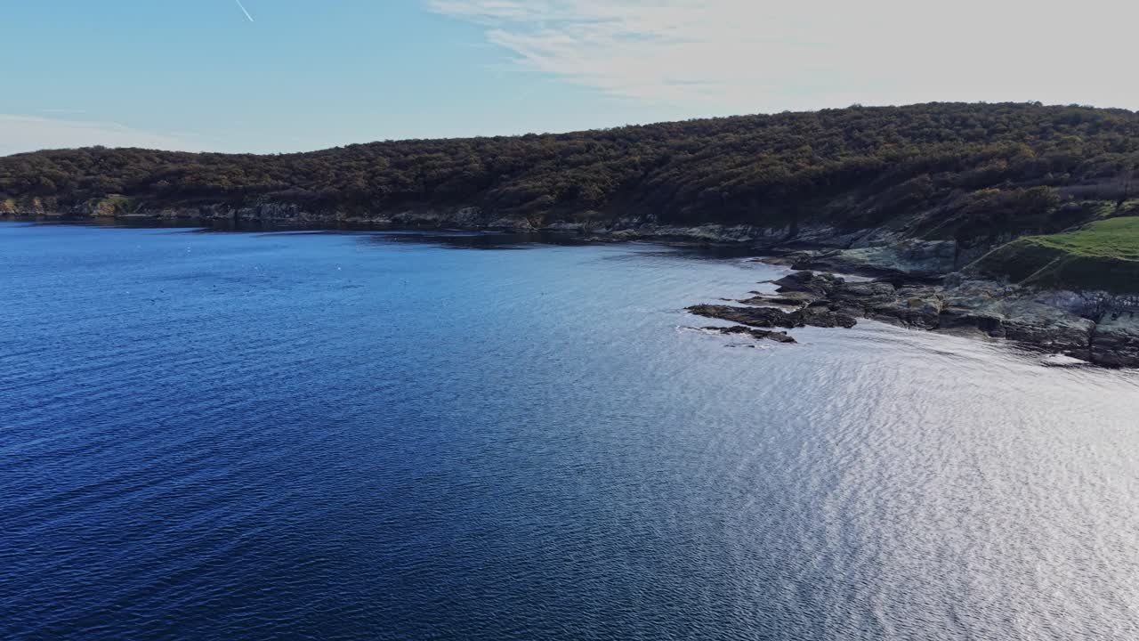 Serene aerial view of calm blue sea meeting rocky coastline