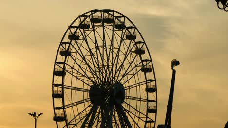 ferris wheel silhouette against orange sunset sky