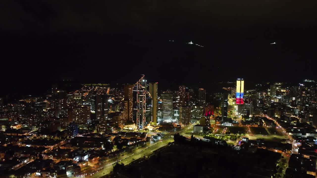 drone panorámico filmado frente al centro iluminado de bogotá, noche en colombia