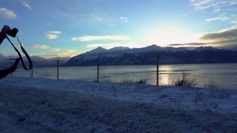 silhouette of a woman taking a winter photo of a mountain in alaska along the river