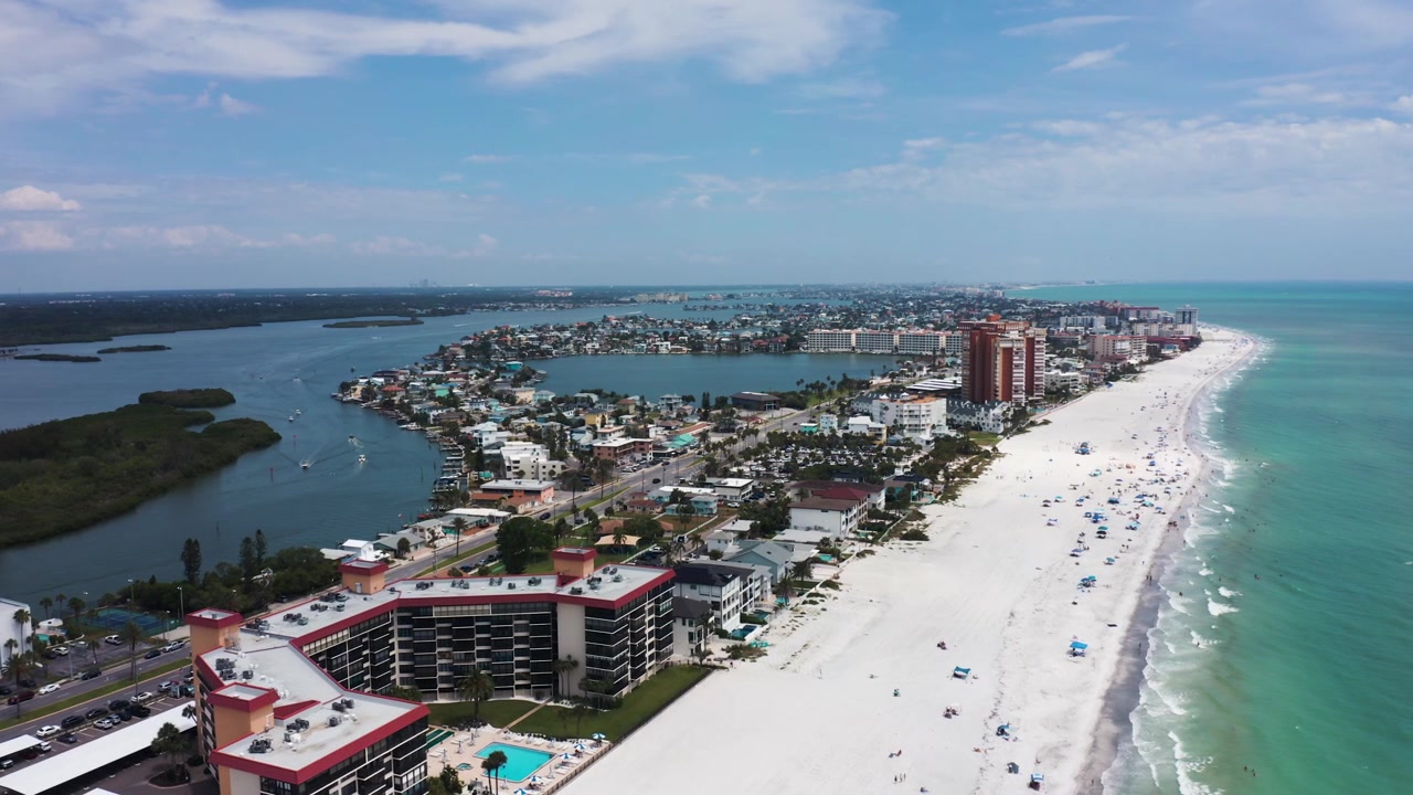 Veduta aerea che cattura la vivace costa di Indian Shores Beach, evidenziando edifici residenziali e acque turchesi. Adatto per contenuti immobiliari e di viaggio.