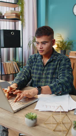 indian man accountant works with financial graph documents calculate taxes for charts at office