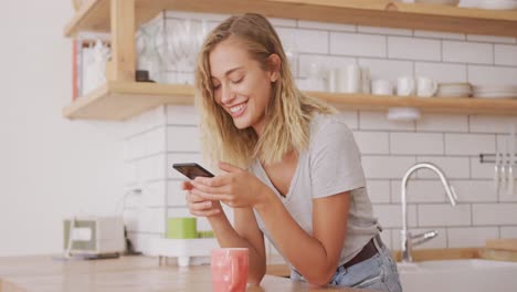 mujer riendo mientras usa teléfono inteligente en casa