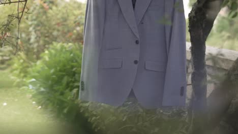 un traje de novio colgado en una rama de un árbol en un jardín, listo para el día de la boda