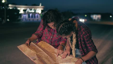 Two-young-women-hitchhiker-searching-for-direction-looking-at-the-map,-young-women-hitchhiking-on-a-road-in-the-city