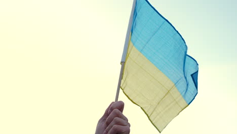 hand waving ukrainian flag at a protest, prague, close up slow motion