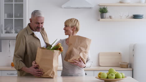 couple shopping and carrying groceries in a kitchen