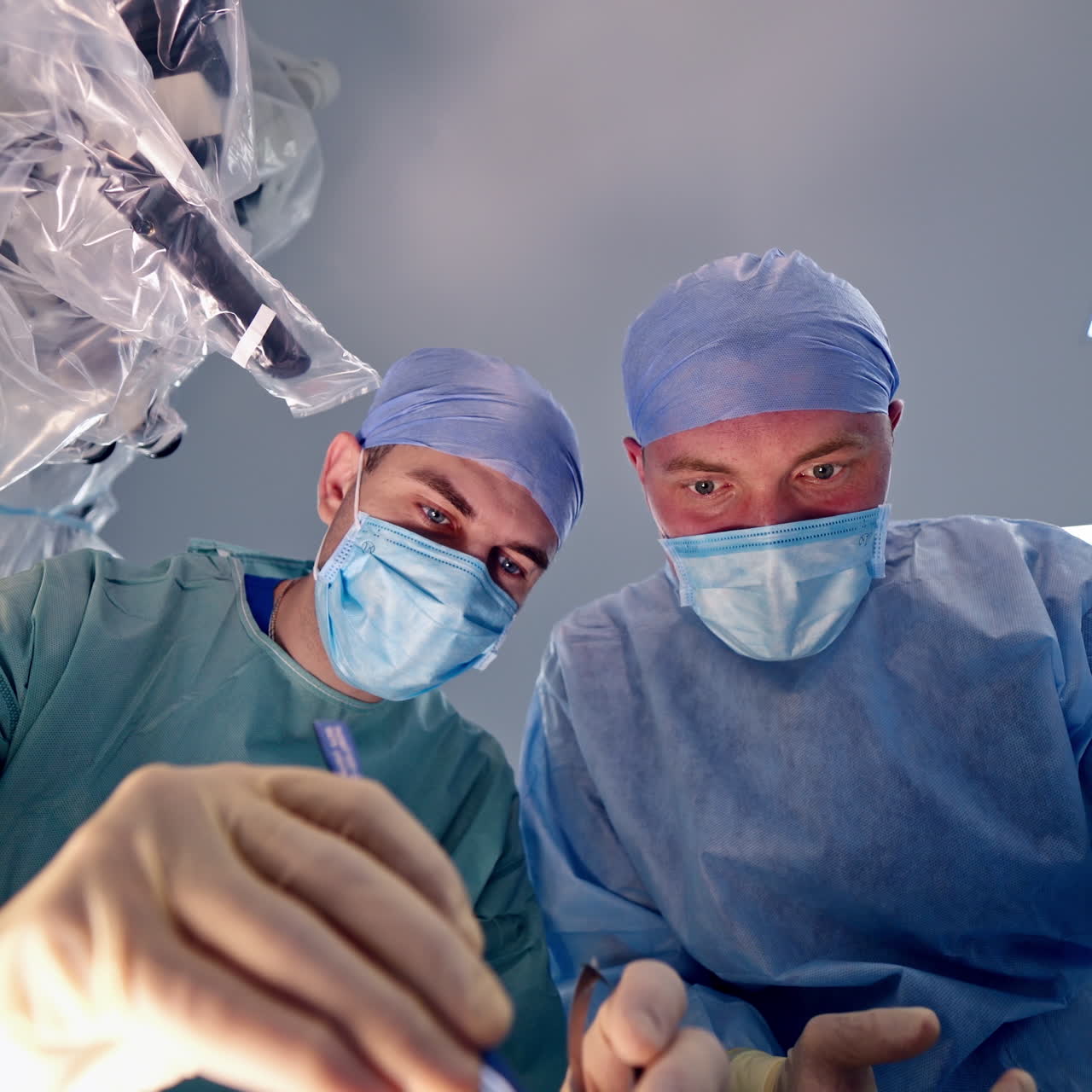 Two medical specialists in masks perform an operation. Portrait of surgeons during operating theatre on modern equipment background in clinic.