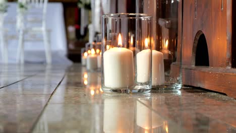 decorations in the church made of burning candles in glass vases for the wedding ceremony