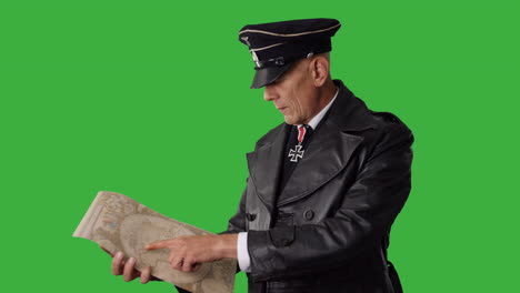 a german world war two ss officer in black uniform reading a map on green screen