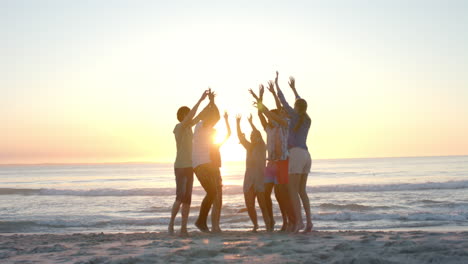 diverse group of friends celebrate at the beach at sunset at a party