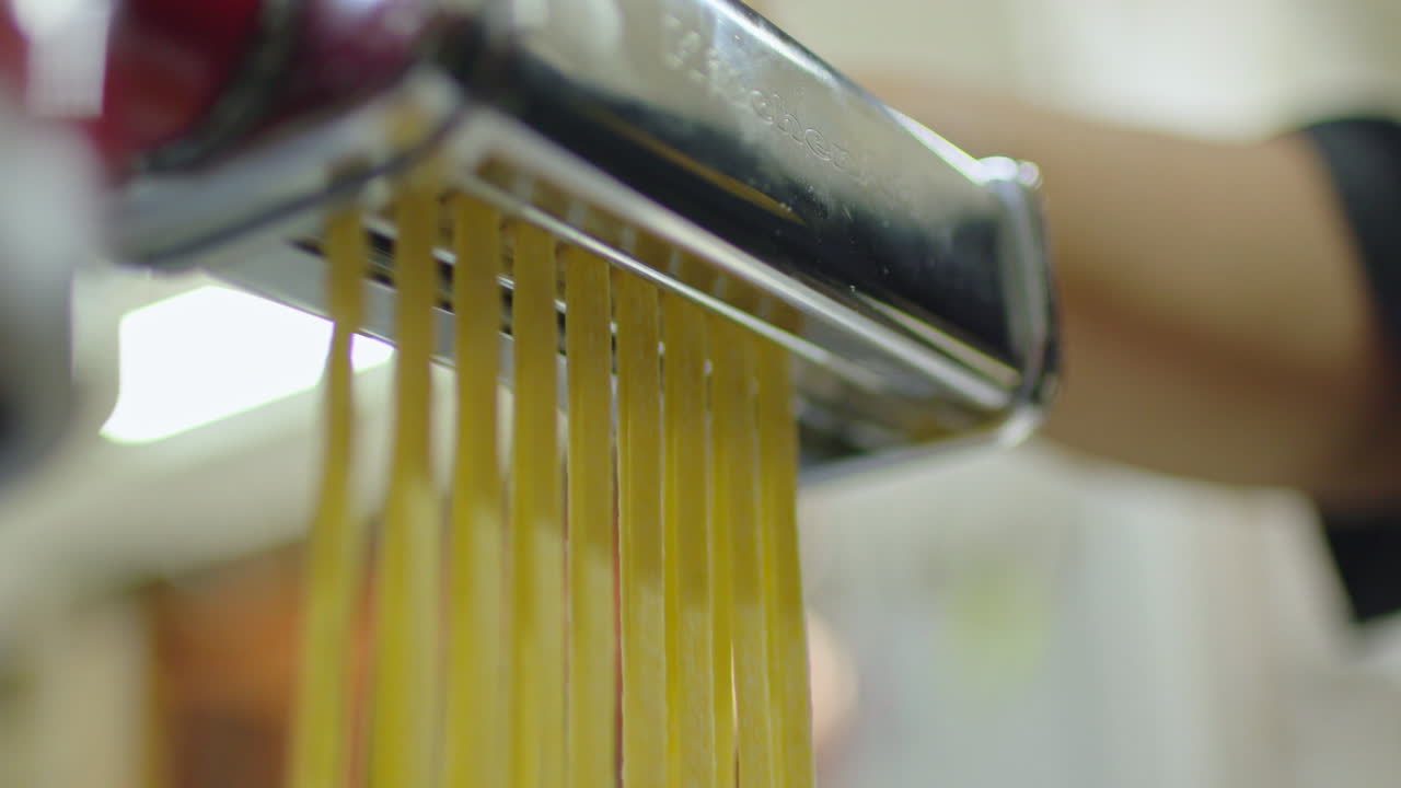 Close up of a pasta cutting machine making traditional italian fettuccini.