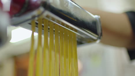 close up of a pasta cutting machine making traditional italian fettuccini.