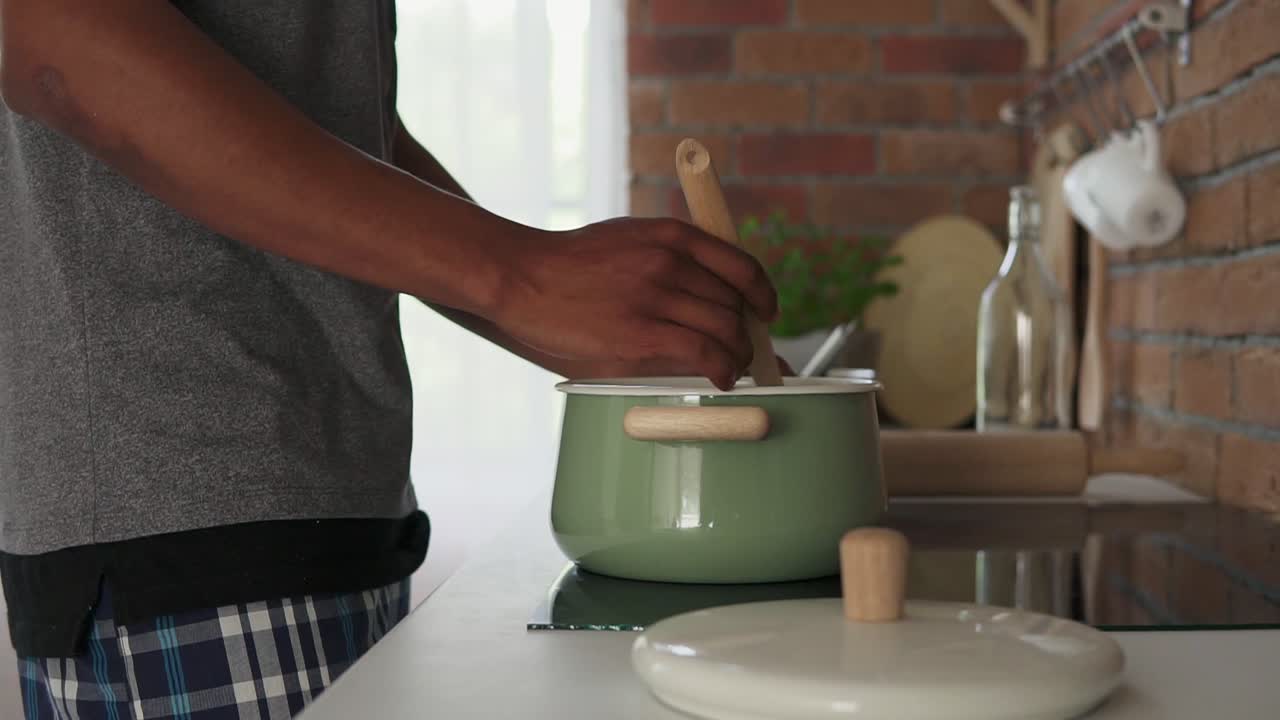 hombre africano hirviendo agua en una olla de pie en la cocina, disparo en cámara lenta