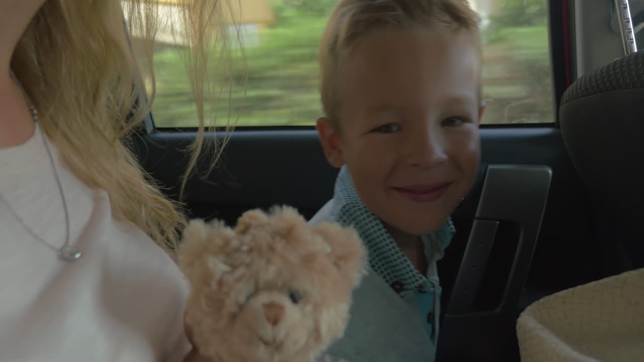 Bambino che viaggia in auto con la madre e un giocattolo.