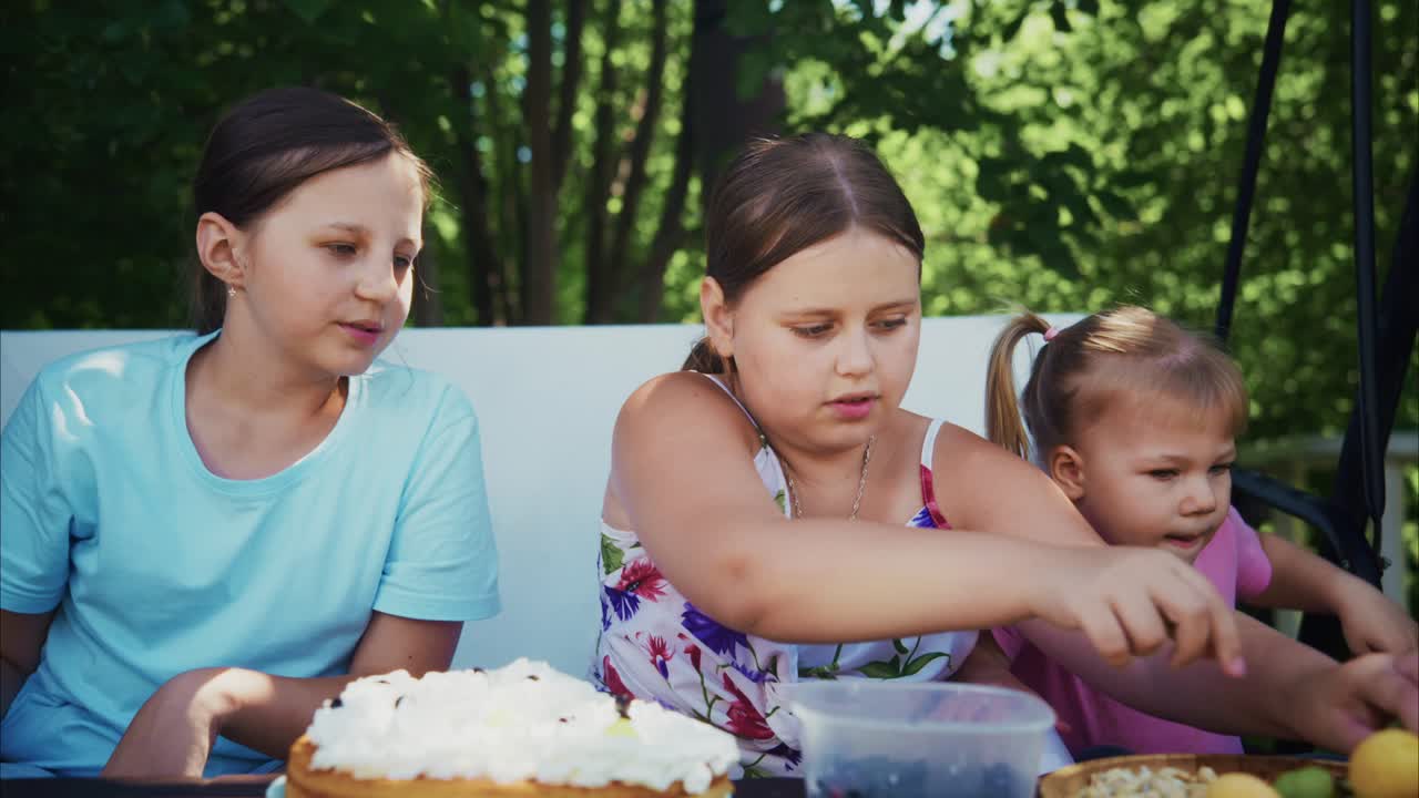 Three girls enjoying a summer picnic outdoors with delicious desserts and joyful atmosphere