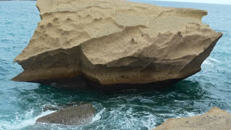 tilt up view, massive sharp sandstone cliff located in middle of ocean