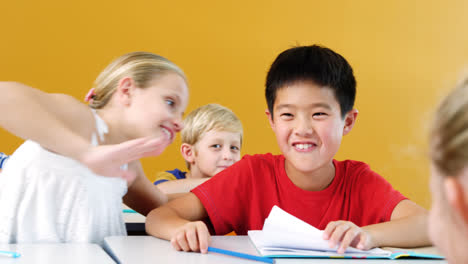 schoolgirl whispering into his friend s ear in classroom