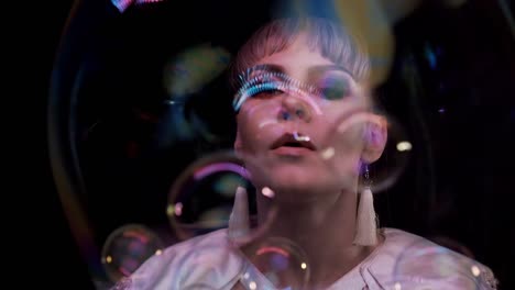 close up: cute girl does tricks with soap bubbles. she blows a lot of small bubbles into big bubble