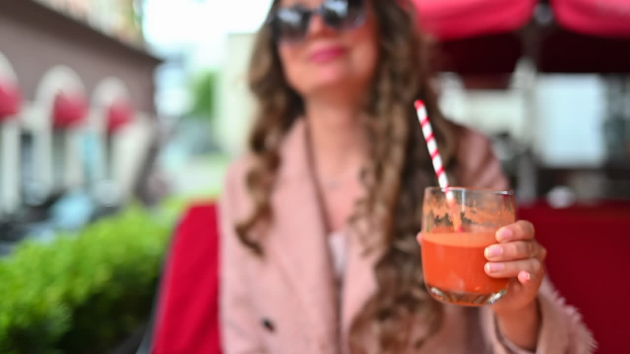 Donna che beve succo di carota fresco sulla terrazza di un ristorante
