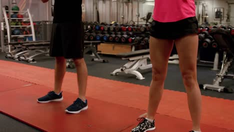 couple doing weighted squats in gym