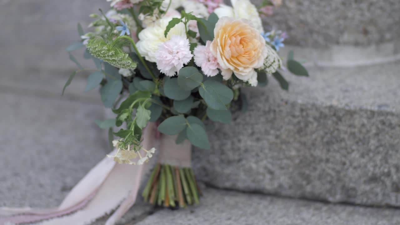 bouquet da sposa con fiori vibranti con fascia in velluto rosa su scale in pietra