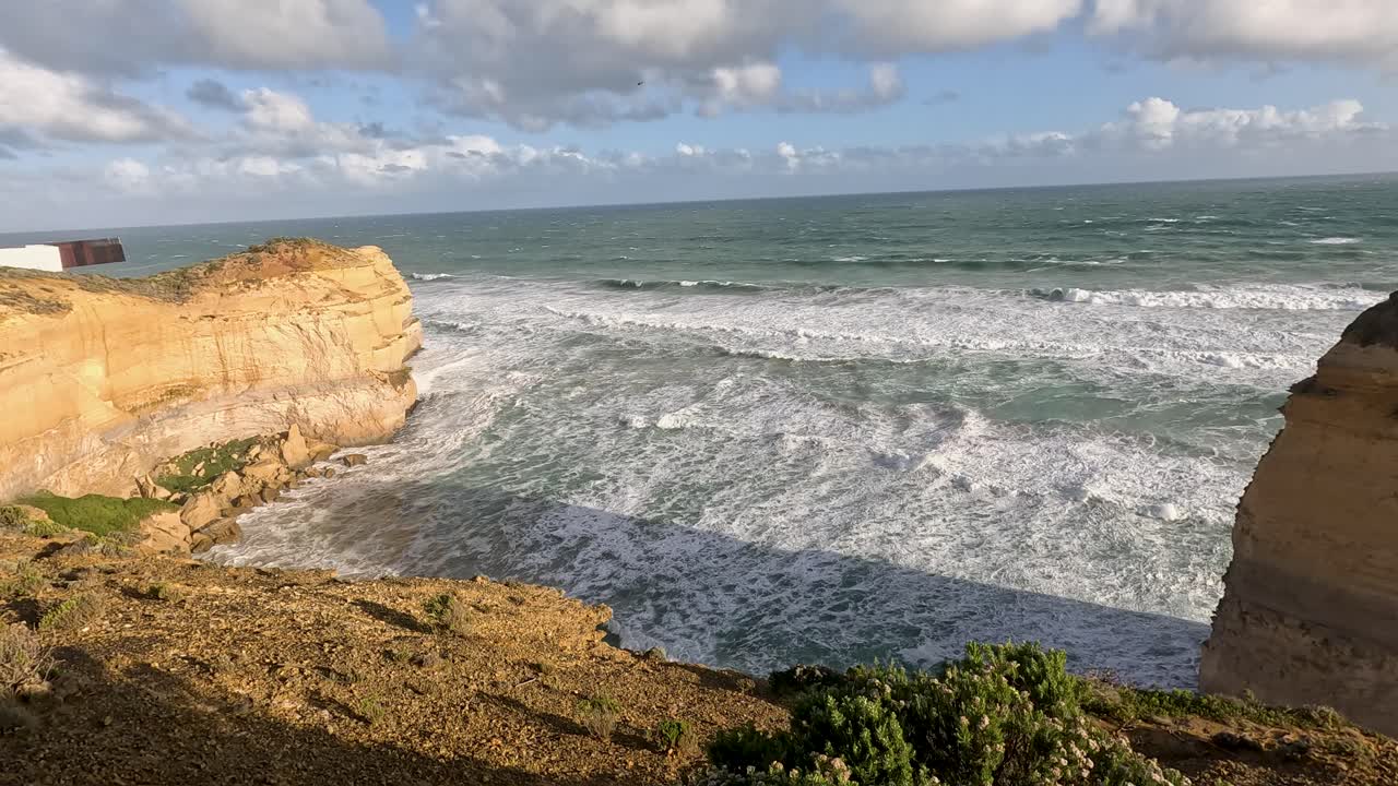 Ocean waves hitting cliffs under a cloudy sky