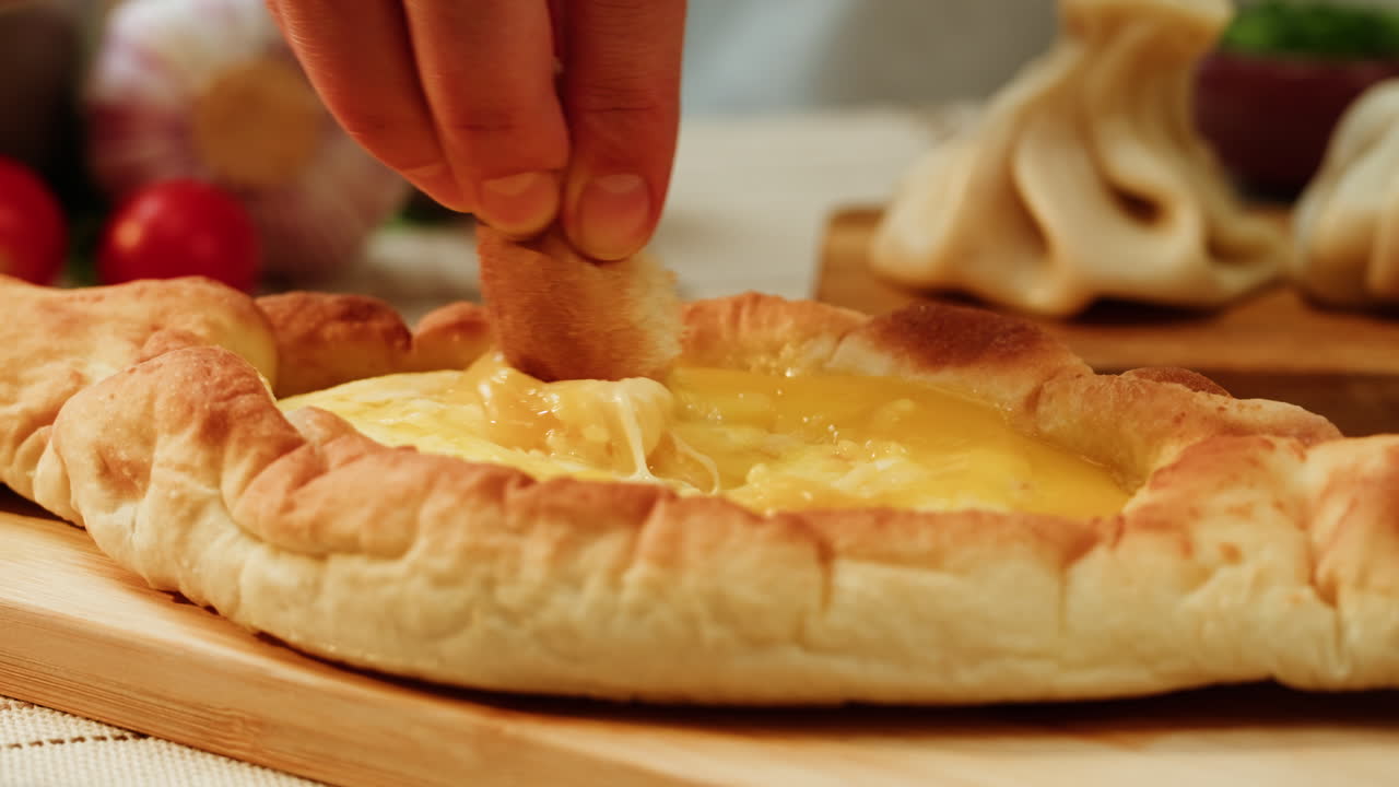 Delicious Khachapuri with a piece of bread dipped in cheese