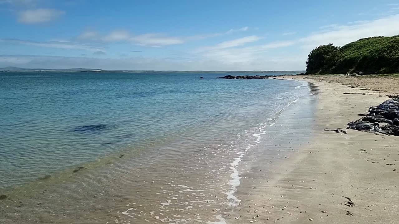 Gorsedd Penrhyn secluded Welsh beach as slow motion waves lap against sandy white shoreline