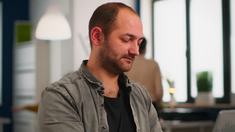 Close-up-of-authentic-caucasian-manager-sitting-at-table-in-modern-startup-business-office