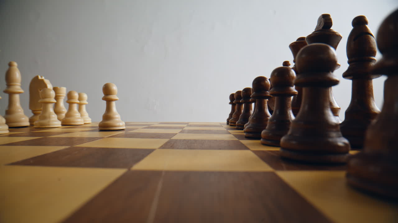 Hand putting brown chess item making first move on chessboard alone closeup