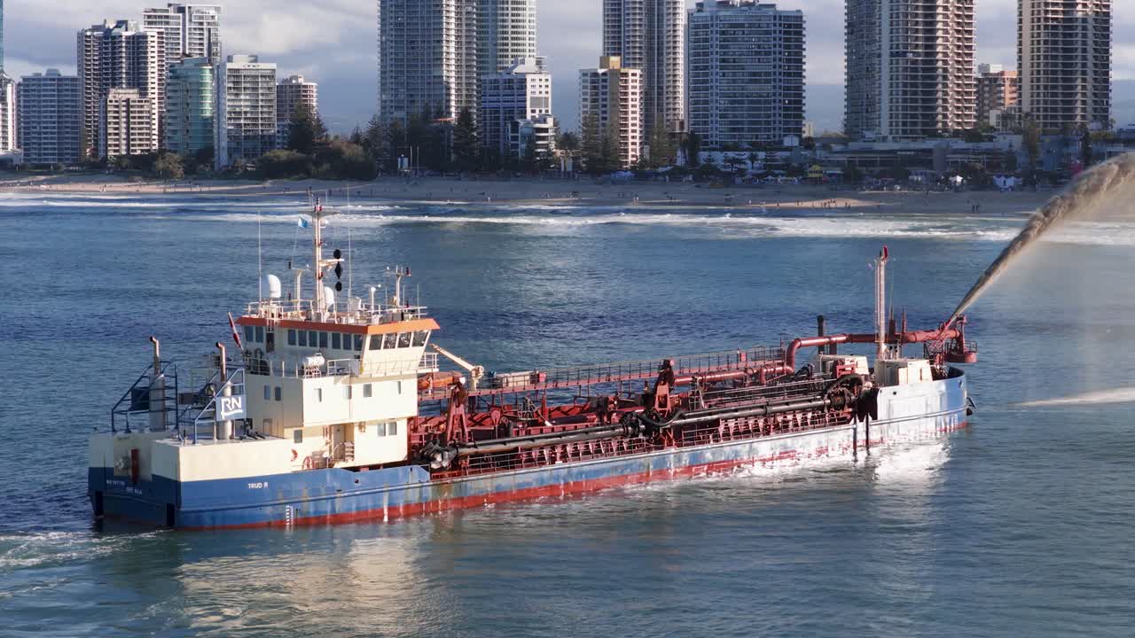 Aerial view of a dredging ship pumping sand in Gold Coast waters, with city skyline in the background during sunset
