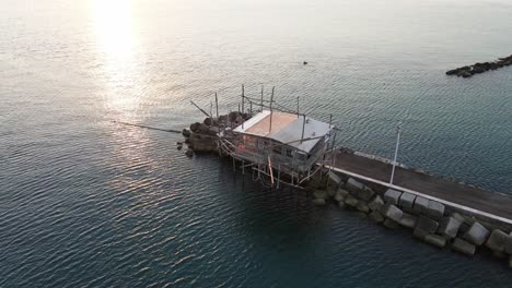 Vista-Aérea-De-Un-Trabucco,-Máquina-De-Pesca-Tradicional,-En-La-Costa-Italiana,-Al-Atardecer