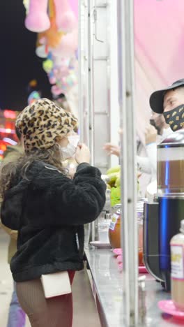 people wearing masks at a food stall during a night event