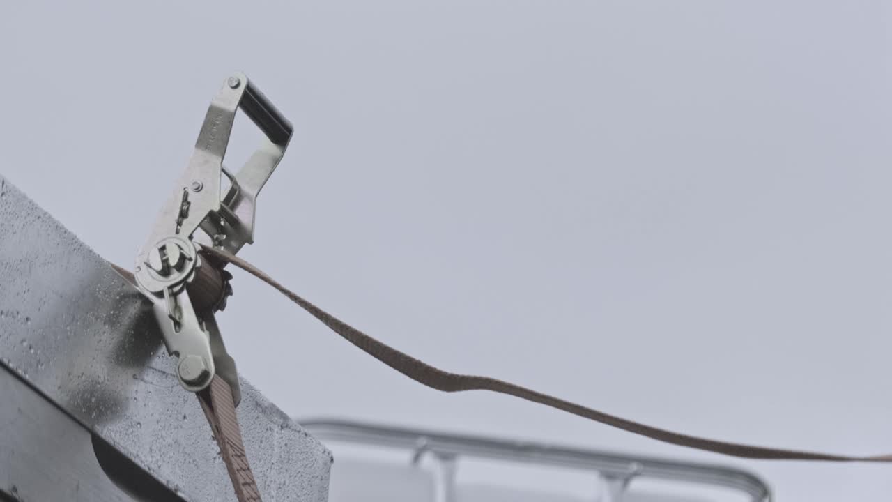 타이 다운 래칫 스트랩을 고정하기 위해 남성 근로자가 무릎을 꿇는 슬로우 모션