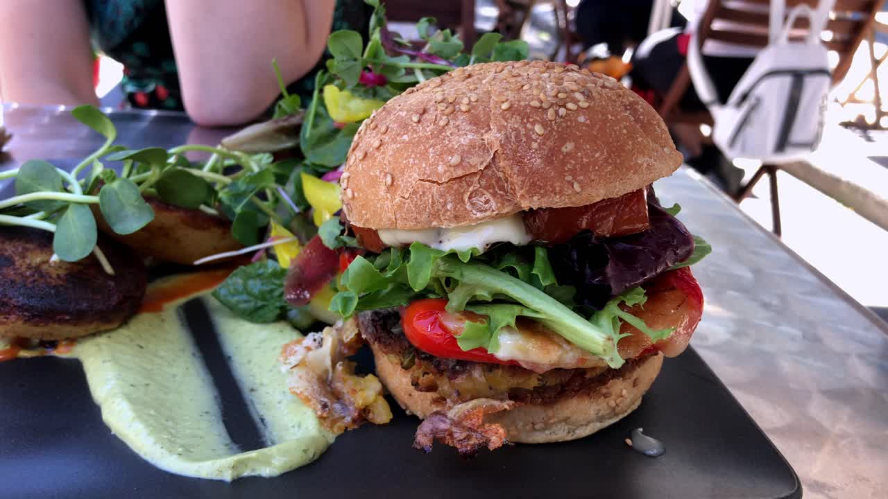 ensalada grande y hamburguesa vegana en un restaurante al aire libre