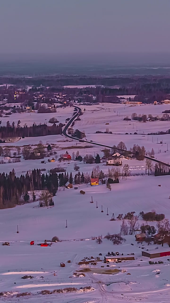 Campagna invernale con campi innevati e case rurali nella morbida luce del crepuscolo