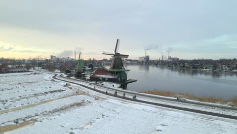 Gruppe-Von-Touristen,-Die-Im-Winter-Entlang-Der-Berühmten-Windmühlen-In-Zaanse-Schans-Radeln