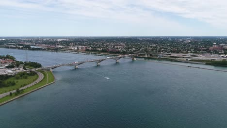 aerial footage of a boat travelling under the fort erie peace bridge, as cars travel the bridge from fort erie to buffalo