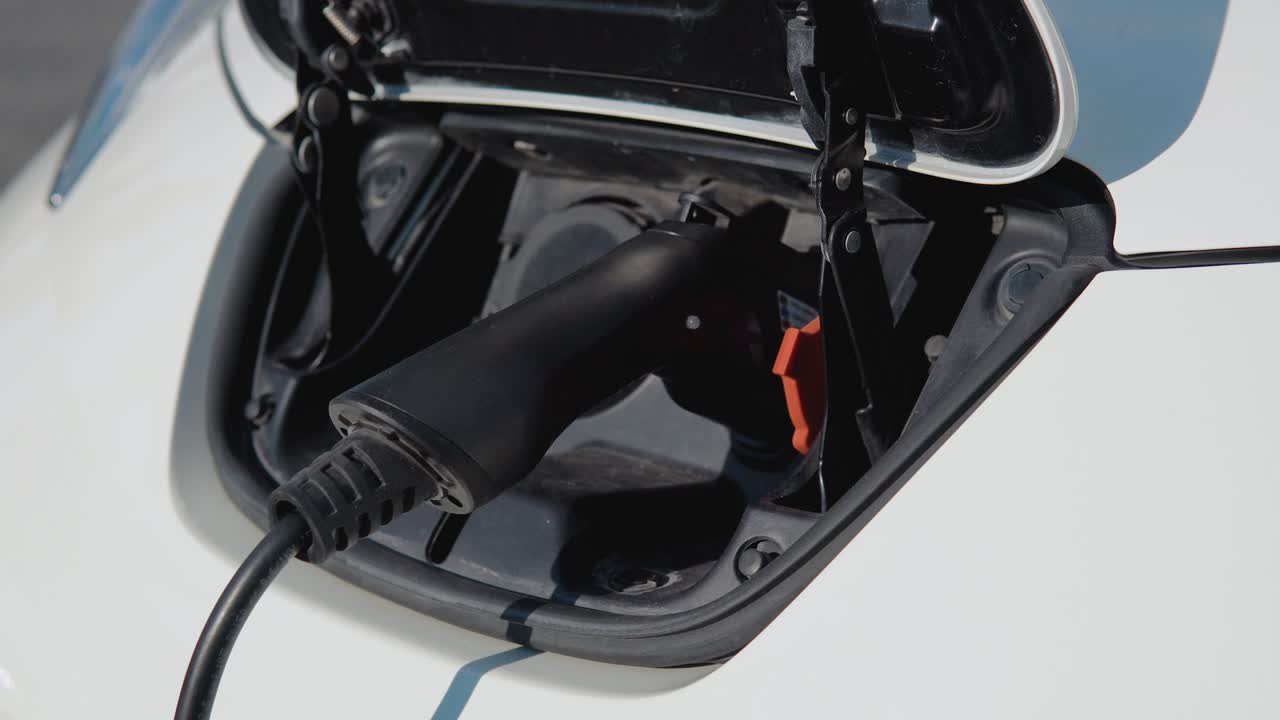 주차장에서 전원 케이블을 통해 전기 배터리를 충전하는 전기 자동차