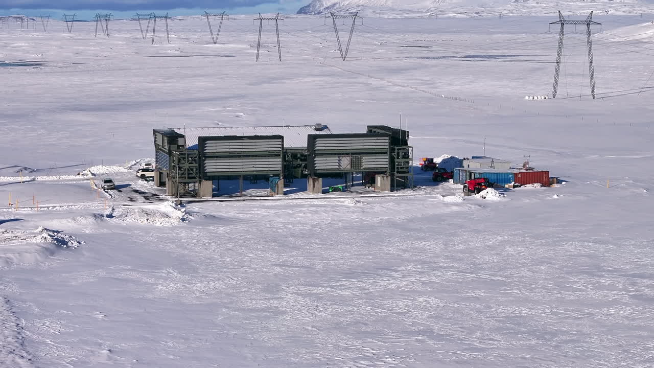Snow-covered direct air capture facility in Iceland with truck in front, wide shot
