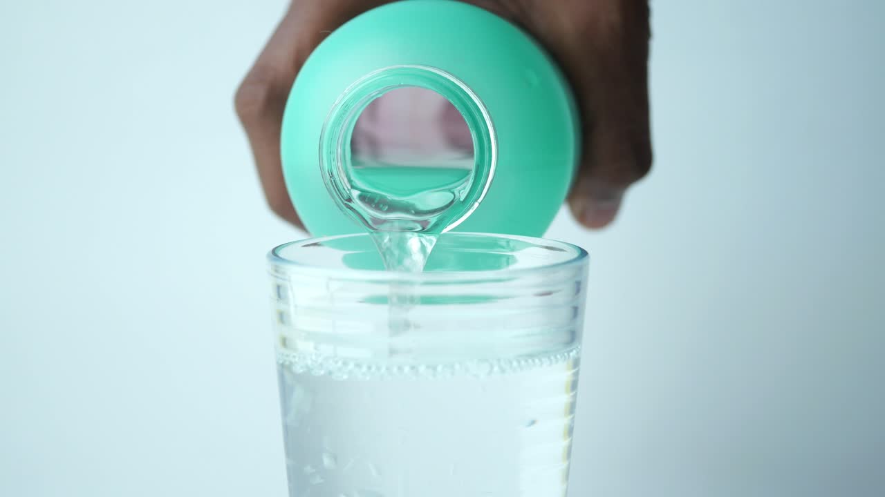 vertiendo agua en un vaso de una botella