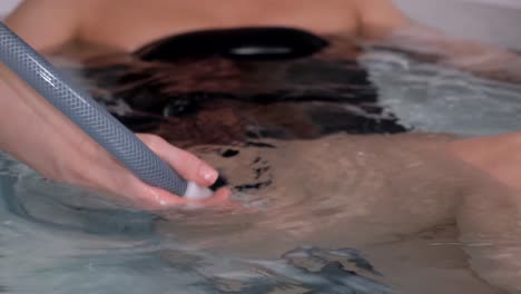 a relaxed woman receives a hydromassage from a professional beautician in a spa center.