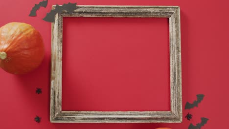 video of frame with copy space, halloween decorations and pumpkin on red background