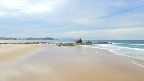 scenic rock formation at currumbin beach in queensland, australia with city of gold coast in distance