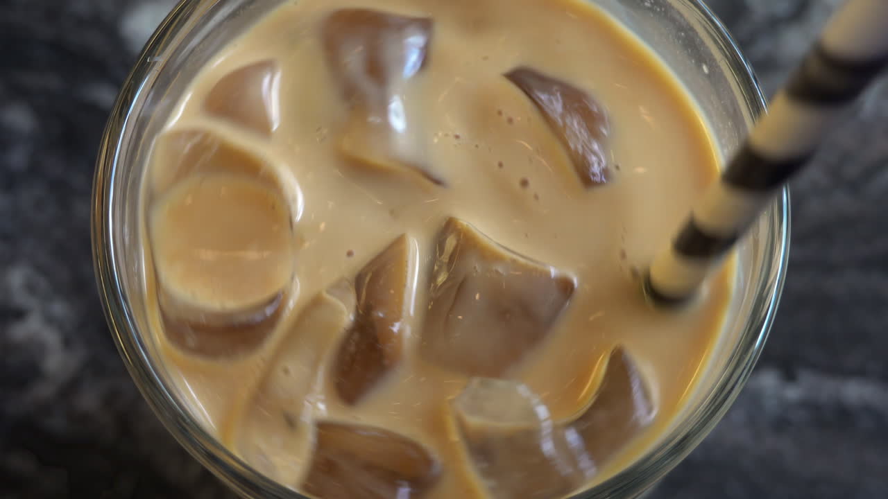 Close up of an iced latte being swirled with a straw